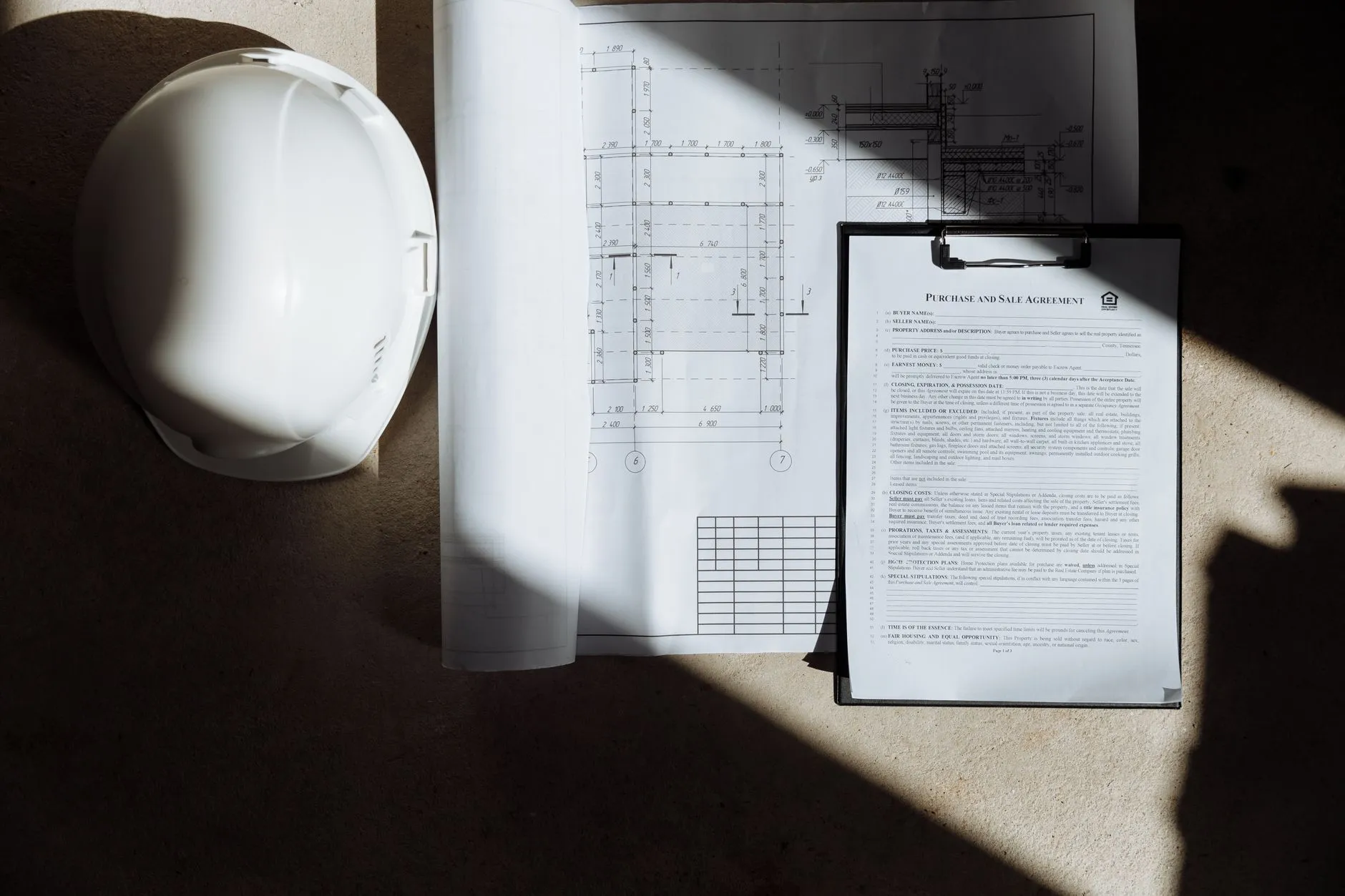 A site supervisor reviewing construction drawings and project plans at a desk — Avaib