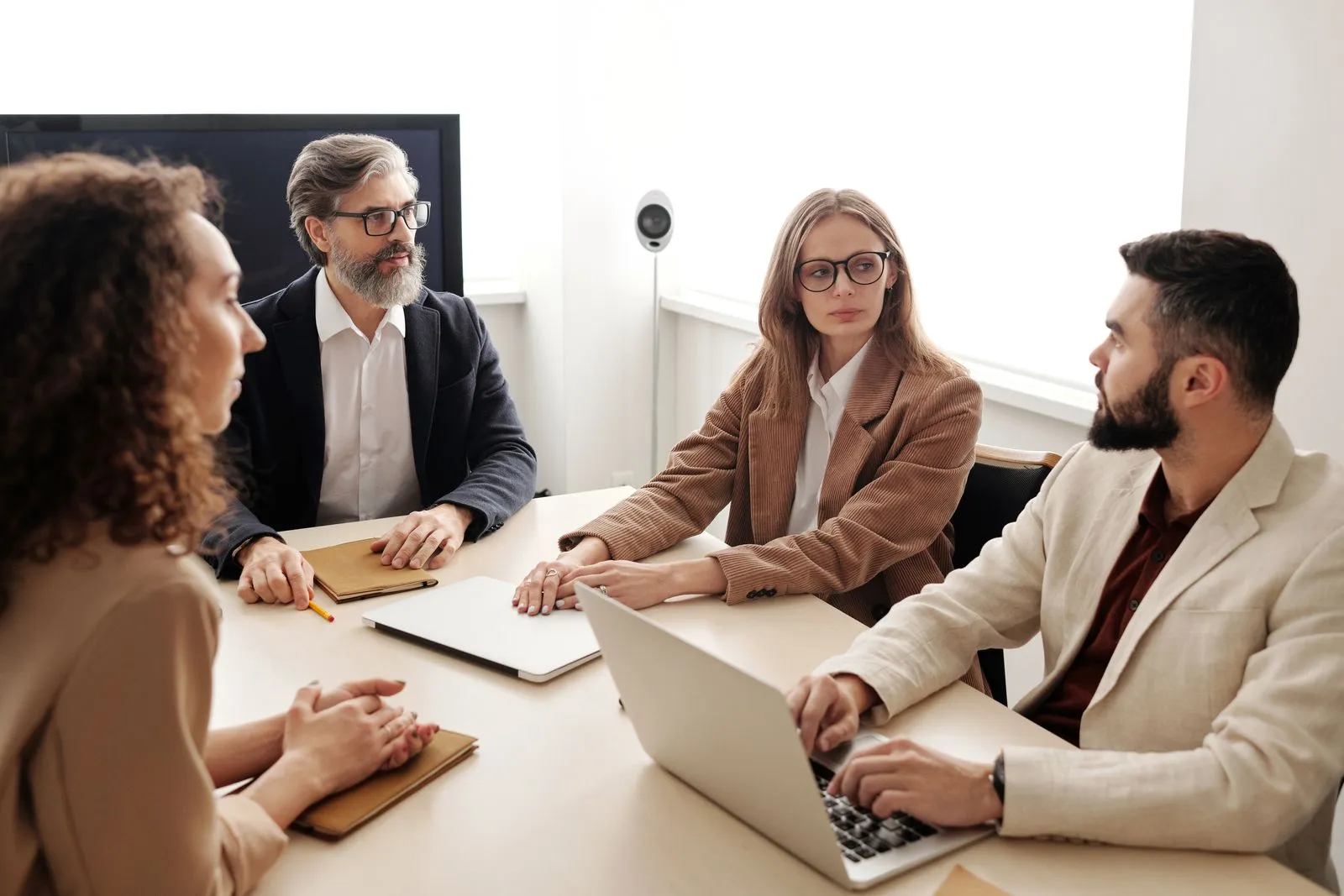 Consultants discussing work around a boardroom table with laptops — Avaib